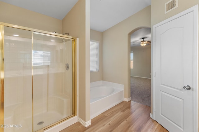 bathroom featuring ceiling fan, shower with separate bathtub, and hardwood / wood-style flooring