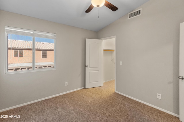 empty room featuring lofted ceiling, light carpet, and ceiling fan