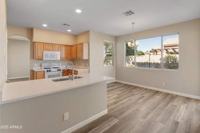 kitchen featuring a healthy amount of sunlight, a chandelier, sink, and white appliances