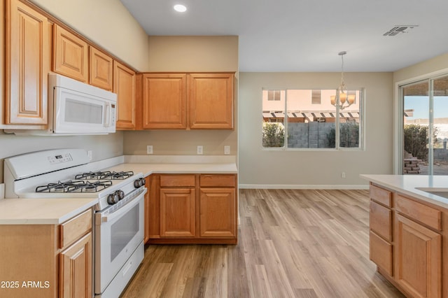 kitchen featuring white appliances, light hardwood / wood-style flooring, a chandelier, and hanging light fixtures