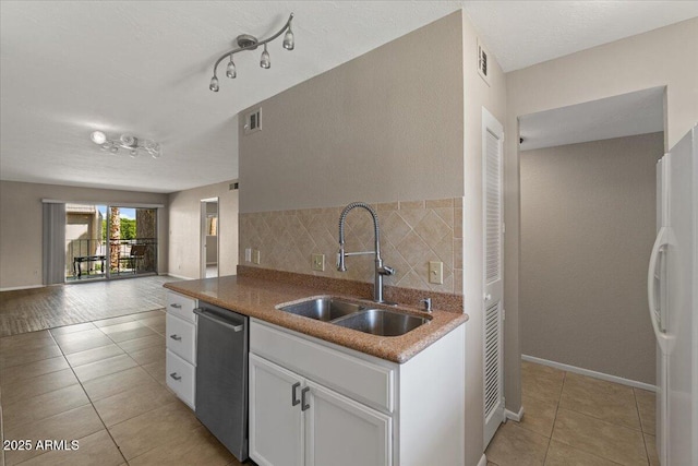 kitchen featuring light tile patterned flooring, a sink, visible vents, stainless steel dishwasher, and freestanding refrigerator