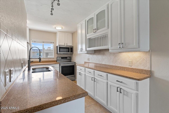 kitchen featuring appliances with stainless steel finishes, white cabinets, a sink, and backsplash