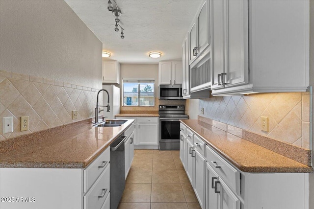 kitchen featuring light tile patterned floors, a textured ceiling, a sink, white cabinetry, and appliances with stainless steel finishes