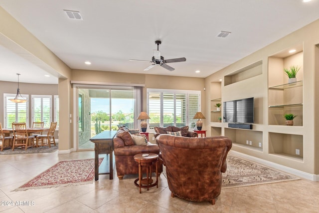 living room with built in shelves, ceiling fan, and light tile patterned floors