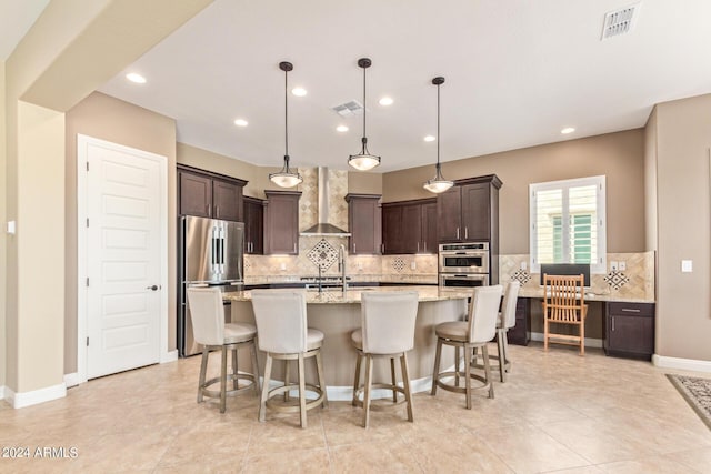 kitchen with dark brown cabinetry, wall chimney exhaust hood, decorative light fixtures, and appliances with stainless steel finishes