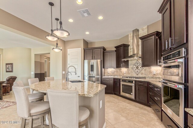 kitchen with appliances with stainless steel finishes, backsplash, a center island with sink, and a breakfast bar area