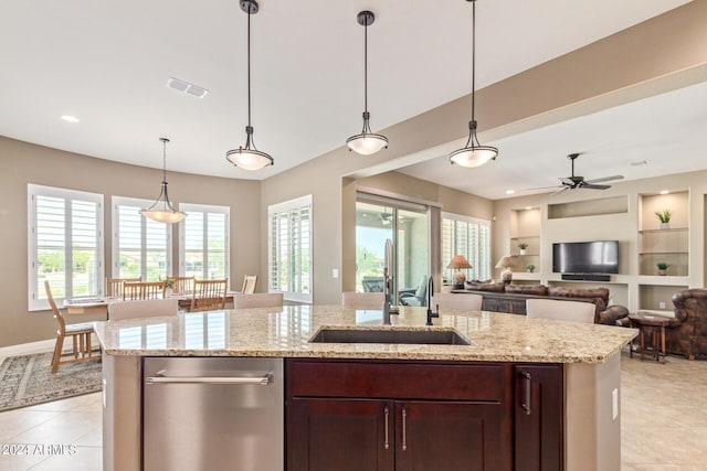 kitchen with built in shelves, ceiling fan, sink, hanging light fixtures, and an island with sink