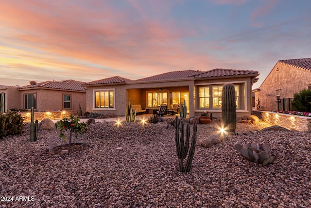 back house at dusk with an outdoor hangout area, ceiling fan, and a patio area