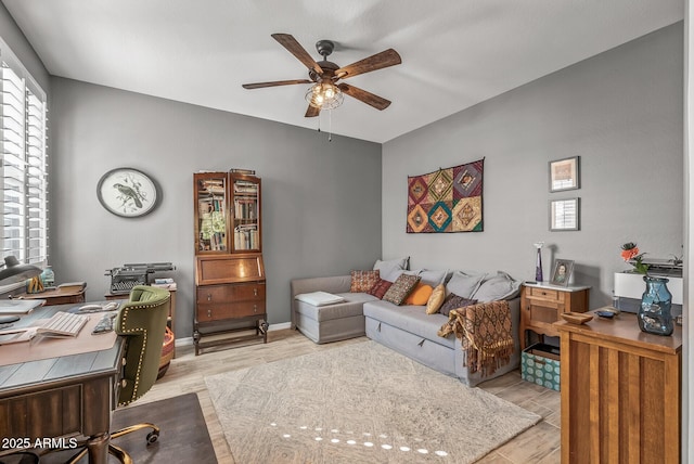 home office featuring light wood-style floors, baseboards, and a ceiling fan