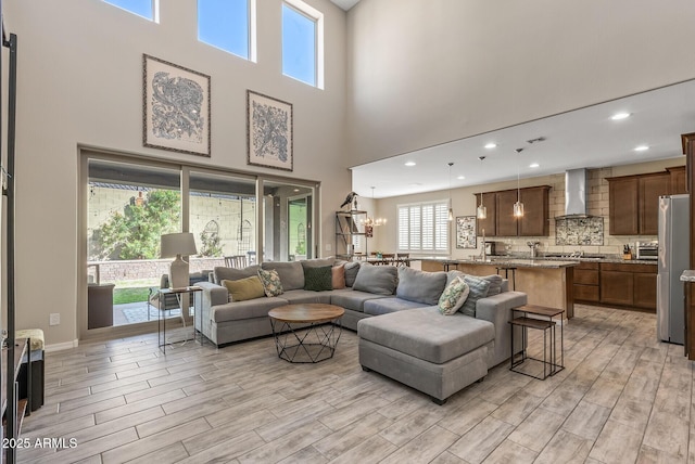 living area with a chandelier, baseboards, light wood-style flooring, and recessed lighting