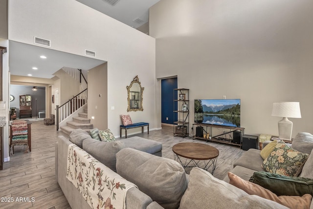 living room featuring light wood-type flooring, stairway, and visible vents