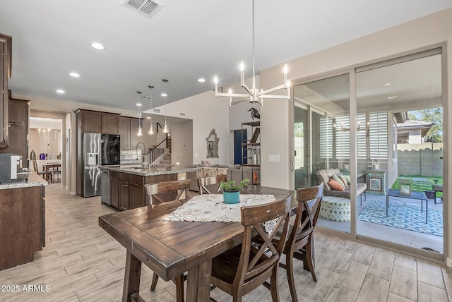 dining area featuring stairway, wood tiled floor, visible vents, and an inviting chandelier