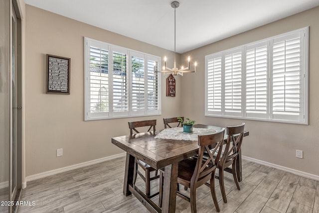 dining room with light wood-type flooring, a notable chandelier, and baseboards