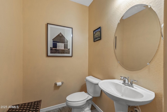 bathroom featuring wood finished floors, a sink, toilet, and baseboards