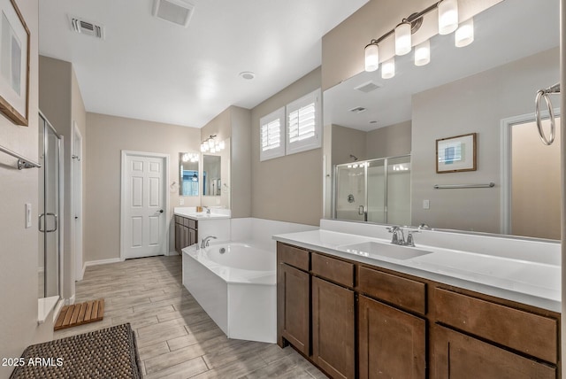 full bath featuring a garden tub, a sink, visible vents, and a shower stall