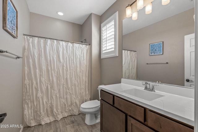 bathroom with toilet, a shower with curtain, wood finished floors, and vanity