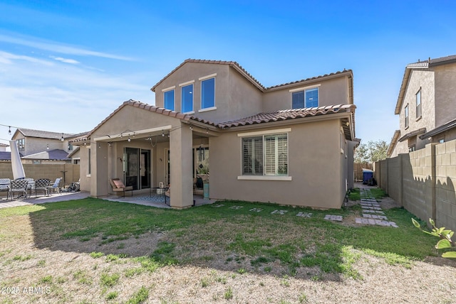 back of property with a yard, stucco siding, a patio area, a fenced backyard, and a tiled roof