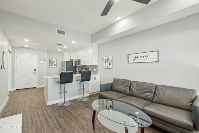 living room with wood-type flooring and ceiling fan