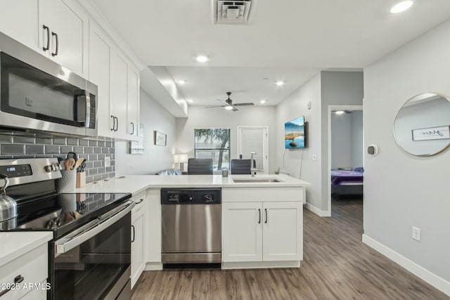 kitchen featuring sink, white cabinetry, stainless steel appliances, tasteful backsplash, and kitchen peninsula