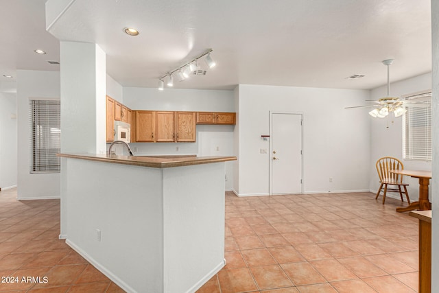 kitchen featuring kitchen peninsula, ceiling fan, track lighting, and light tile patterned floors