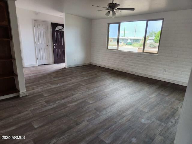 unfurnished room with brick wall, dark hardwood / wood-style floors, and ceiling fan