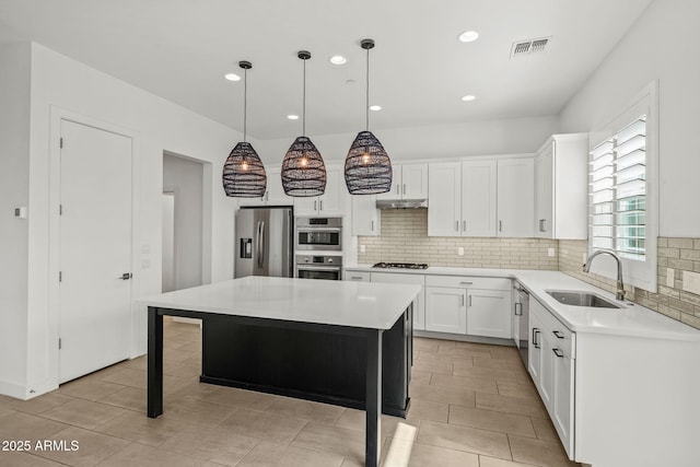 kitchen with visible vents, under cabinet range hood, light countertops, stainless steel appliances, and a sink