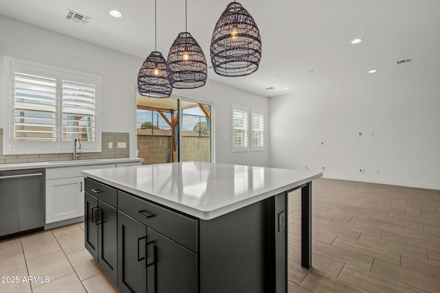 kitchen featuring tasteful backsplash, visible vents, light countertops, stainless steel dishwasher, and a sink