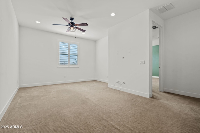 spare room featuring light colored carpet, a ceiling fan, visible vents, and baseboards