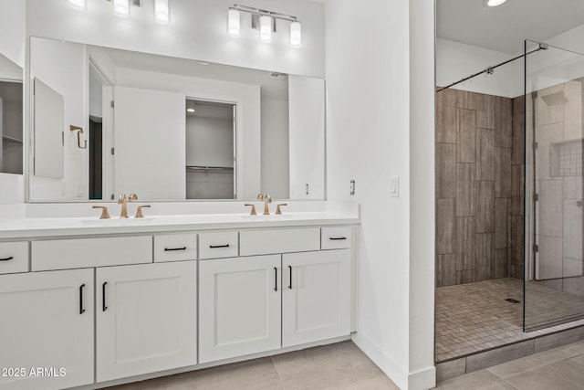 bathroom with tile patterned floors, double vanity, a tile shower, and a sink