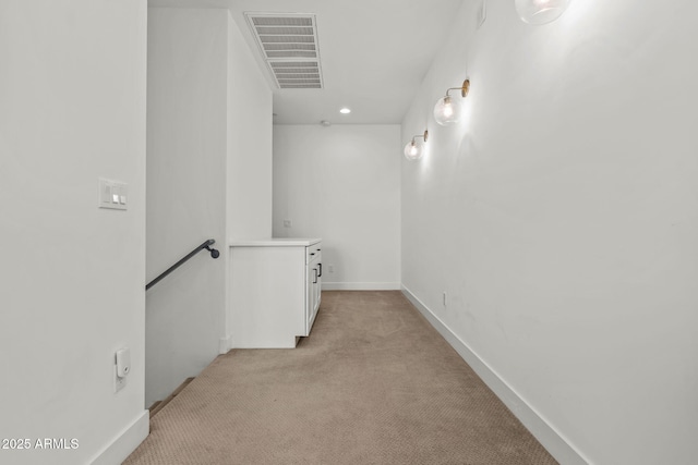 hall featuring visible vents, an upstairs landing, light colored carpet, and baseboards