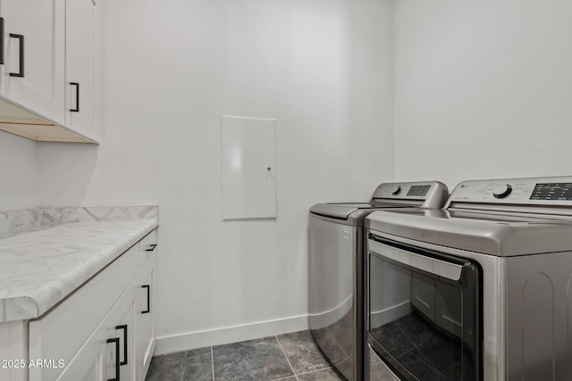 washroom featuring baseboards, cabinet space, and separate washer and dryer