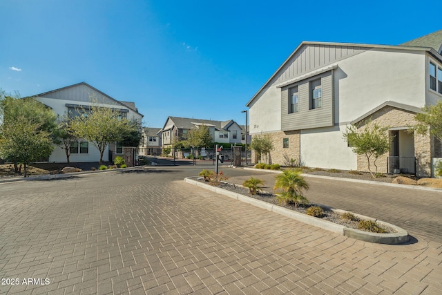 view of road featuring a gated entry, a residential view, curbs, and sidewalks