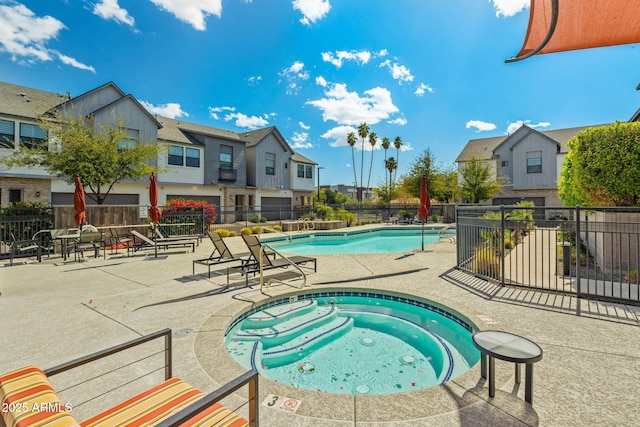 community pool with a residential view, a hot tub, a patio, and fence