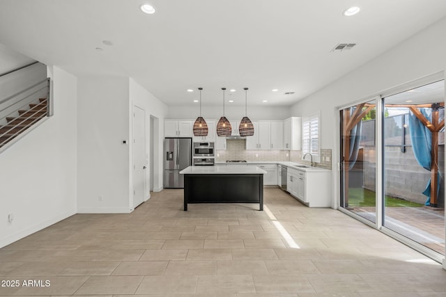 kitchen featuring a sink, tasteful backsplash, appliances with stainless steel finishes, white cabinets, and light countertops