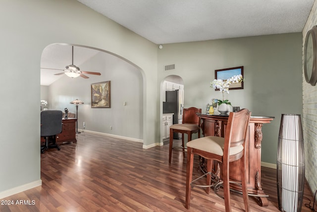 living area with a textured ceiling, ceiling fan, dark hardwood / wood-style flooring, and lofted ceiling