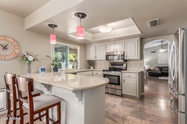 kitchen with kitchen peninsula, pendant lighting, stainless steel appliances, and white cabinetry