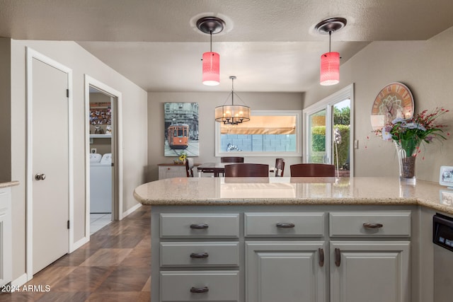 kitchen with washing machine and clothes dryer, hanging light fixtures, gray cabinets, light stone countertops, and a chandelier