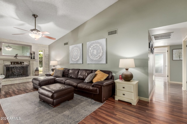 living room featuring dark hardwood / wood-style floors, a textured ceiling, a wealth of natural light, and a brick fireplace