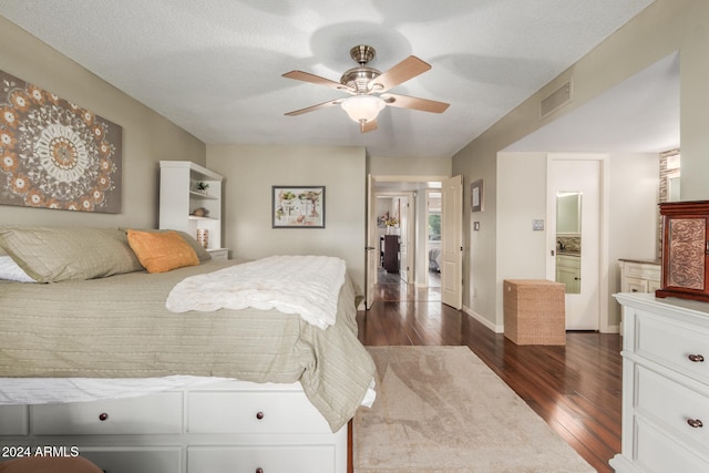 bedroom with a textured ceiling, ensuite bath, ceiling fan, and dark wood-type flooring