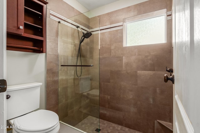 bathroom with a tile shower and toilet