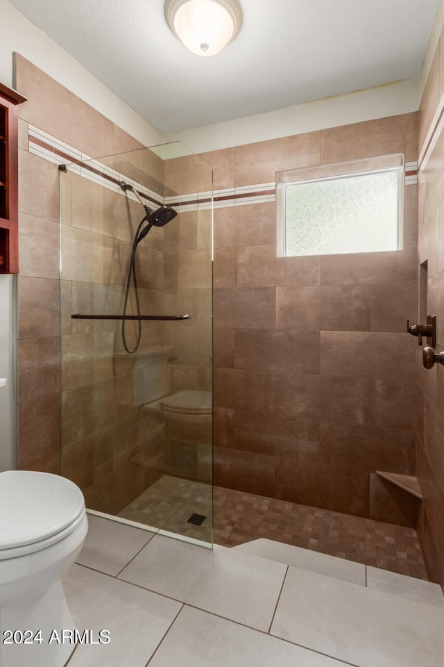 bathroom with tile patterned floors, tiled shower, and toilet