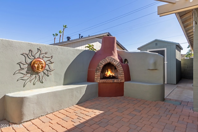 view of patio / terrace featuring an outdoor brick fireplace and a storage shed