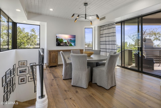 dining space featuring a notable chandelier, wood-type flooring, and wooden ceiling