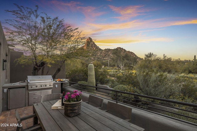 exterior space featuring a mountain view, grilling area, and exterior kitchen