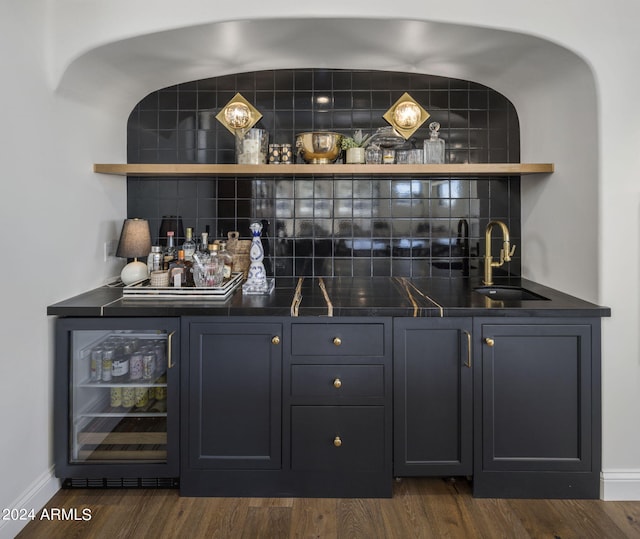 bar featuring sink, dark wood-type flooring, wine cooler, and tasteful backsplash