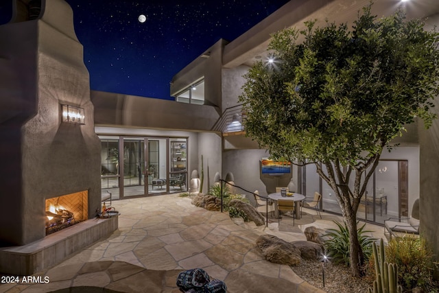 patio at twilight featuring an outdoor fireplace