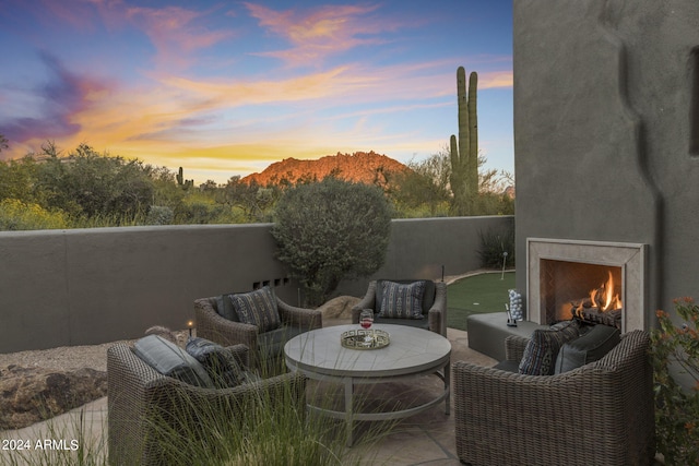 patio terrace at dusk with a mountain view and an outdoor living space with a fireplace