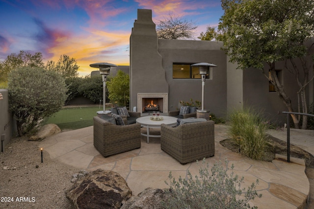 patio terrace at dusk with an outdoor living space with a fireplace