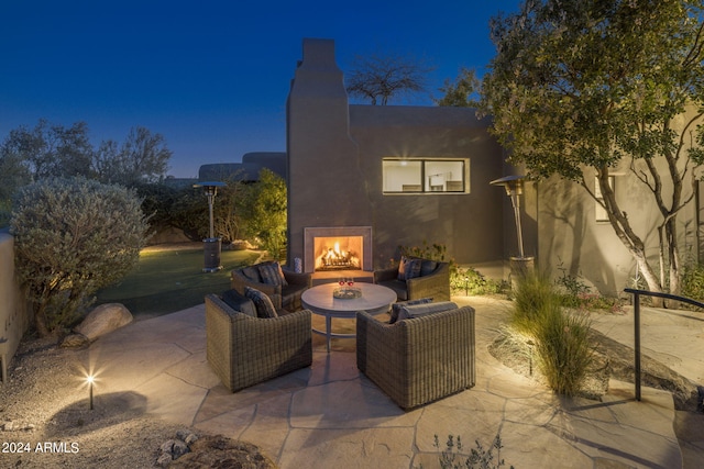 patio at night featuring an outdoor living space with a fireplace