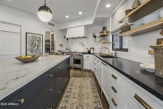 kitchen with dark wood-type flooring, pendant lighting, luxury stove, premium range hood, and sink